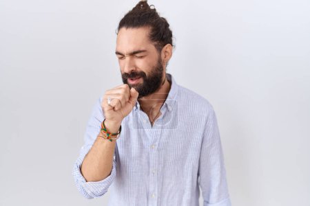 Téléchargez les photos : Homme hispanique avec barbe portant une chemise décontractée se sentant mal et toussant comme symptôme du rhume ou de la bronchite. concept de soins de santé. - en image libre de droit