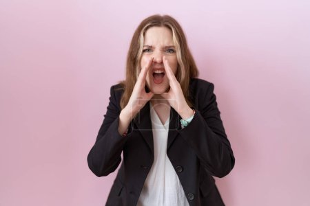 Photo for Young caucasian business woman wearing black jacket shouting angry out loud with hands over mouth - Royalty Free Image
