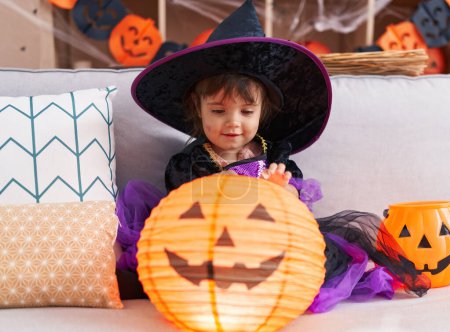 Foto de Adorable chica hispana con disfraz de halloween sosteniendo lámpara de cesta de calabaza en casa - Imagen libre de derechos