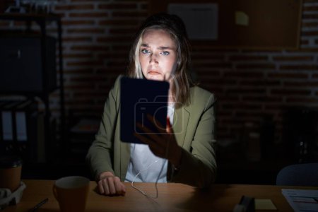 Photo for Blonde caucasian woman working at the office at night depressed and worry for distress, crying angry and afraid. sad expression. - Royalty Free Image