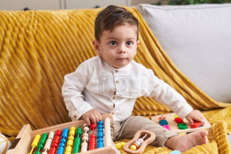 Photo for Adorable hispanic boy playing with abacus sitting on sofa at home - Royalty Free Image