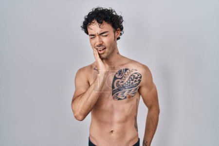Photo for Hispanic man standing shirtless touching mouth with hand with painful expression because of toothache or dental illness on teeth. dentist - Royalty Free Image