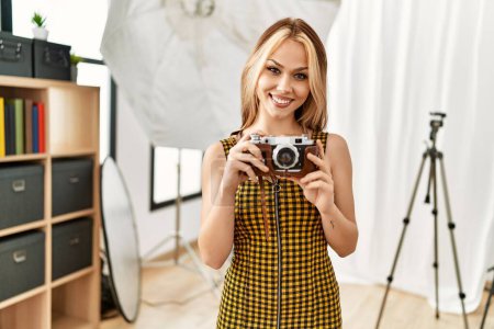 Photo for Young caucasian woman photographer holding vintage camera photo studio - Royalty Free Image