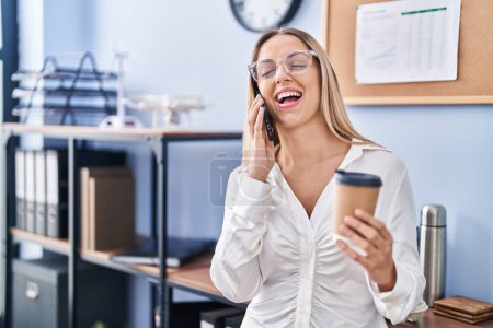 Téléchargez les photos : Jeune femme d'affaires parlant sur le smartphone buvant du café au bureau - en image libre de droit