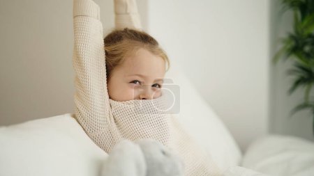 Photo for Adorable blonde girl waking up stretching arms at bedroom - Royalty Free Image