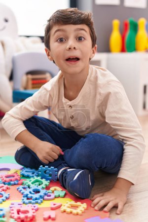 Foto de Adorable hispanic boy smiling confident sitting on floor at kindergarten - Imagen libre de derechos