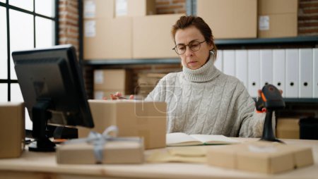 Téléchargez les photos : Moyen âge hispanique femme commerce électronique travailleur d'affaires numérisation paquet en utilisant un lecteur de codes à barres au bureau de l'entrepôt - en image libre de droit