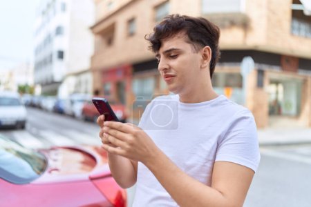 Téléchargez les photos : Homme non binaire utilisant un smartphone avec une expression détendue dans la rue - en image libre de droit