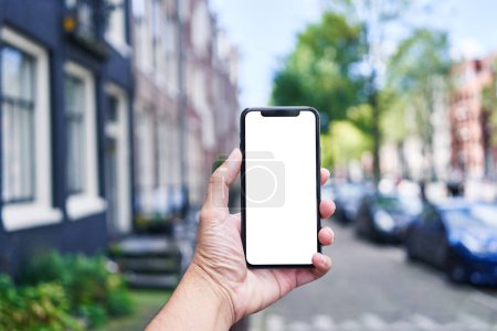 Téléchargez les photos : Homme tenant smartphone montrant écran blanc à Amsterdam - en image libre de droit