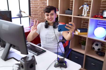Photo for Non binary man streamer smiling confident make selfie by smartphone at gaming room - Royalty Free Image