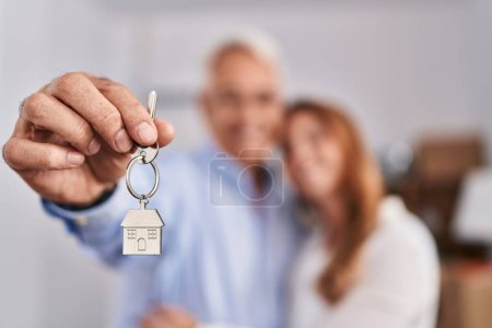 Photo for Middle age man and woman couple hugging each other holding key of new house at new home - Royalty Free Image