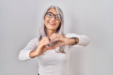 Photo for Middle age woman with grey hair standing over white background smiling in love doing heart symbol shape with hands. romantic concept. - Royalty Free Image