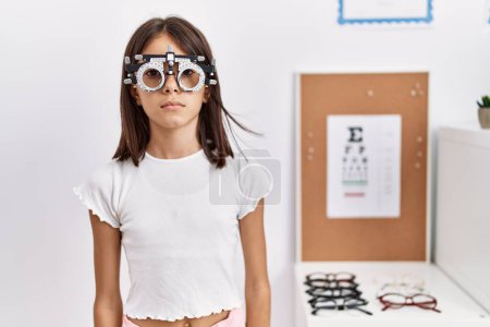Téléchargez les photos : Young hispanic girl wearing optometry glasses with serious expression on face. simple and natural looking at the camera. - en image libre de droit