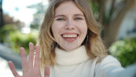 Téléchargez les photos : Jeune femme blonde souriante confiante ayant appel vidéo au parc - en image libre de droit