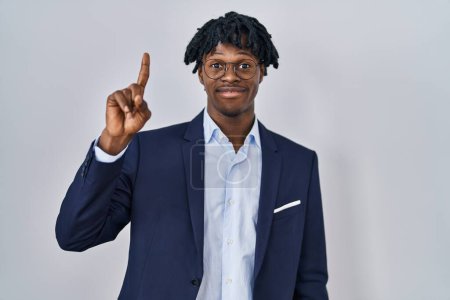 Téléchargez les photos : Young african man with dreadlocks wearing business jacket over white background showing and pointing up with finger number one while smiling confident and happy. - en image libre de droit