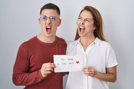 Photo for Mother and son holding my mom is the best card angry and mad screaming frustrated and furious, shouting with anger. rage and aggressive concept. - Royalty Free Image