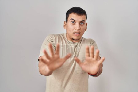 Téléchargez les photos : Jeune homme arabe portant t-shirt décontracté peur et terrifié par l'expression de la peur arrêter geste avec les mains, criant en état de choc. concept de panique. - en image libre de droit
