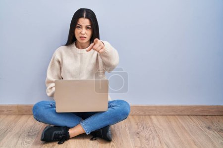 Photo for Young woman using laptop sitting on the floor at home pointing displeased and frustrated to the camera, angry and furious with you - Royalty Free Image