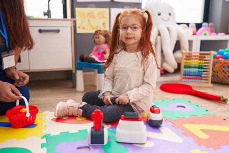 Photo for Adorable redhead girl playing with toys sitting on floor at kindergarten - Royalty Free Image