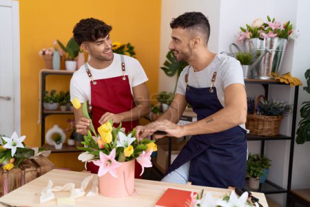 Téléchargez les photos : Two hispanic men florists smiling confident make bouquet of flowers at flower shop - en image libre de droit