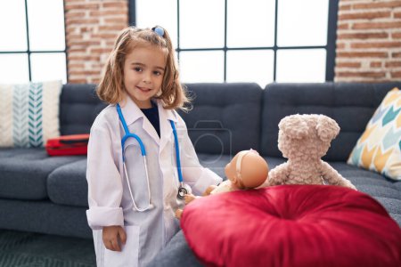 Téléchargez les photos : Adorable hispanique fille portant médecin uniforme auscultant bébé à la maison - en image libre de droit