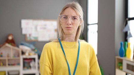 Photo pour Young blonde woman preschool teacher with angry face at kindergarten - image libre de droit