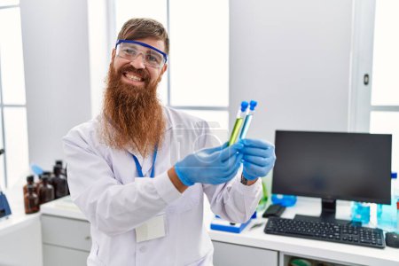 Photo for Young redhead man wearing scientist uniform holding test tubes at laboratory - Royalty Free Image