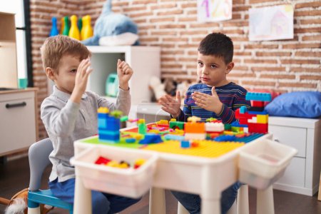 Téléchargez les photos : Deux enfants jouent avec des blocs de construction assis sur la table à la maternelle - en image libre de droit