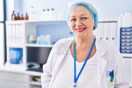 Téléchargez les photos : Middle age blonde woman wearing scientist uniform standing at laboratory - en image libre de droit
