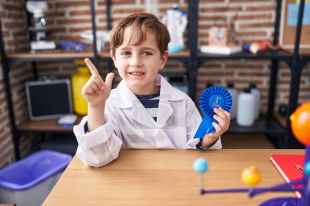 Photo for Little caucasian boy at school scientist laboratory winning first prize smiling happy pointing with hand and finger to the side - Royalty Free Image
