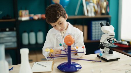 Téléchargez les photos : Adorable hispanic boy astronomer student make planetary work at laboratory classroom - en image libre de droit