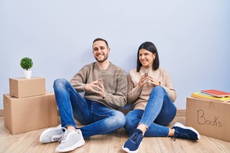 Photo for Young couple moving to a new home hands together and fingers crossed smiling relaxed and cheerful. success and optimistic - Royalty Free Image