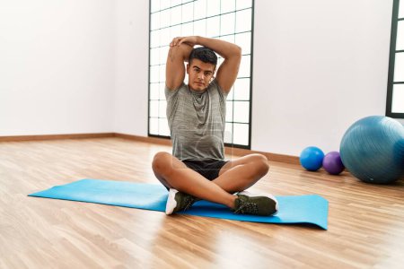 Photo for Young hispanic man stretching at sport center - Royalty Free Image