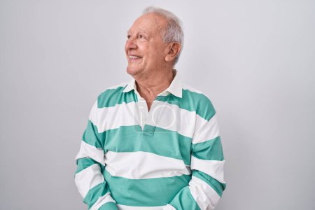 Photo for Senior man with grey hair standing over white background looking away to side with smile on face, natural expression. laughing confident. - Royalty Free Image