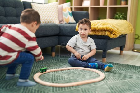 Foto de Two kids playing with train toy sitting on floor at home - Imagen libre de derechos