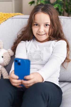Photo for Adorable hispanic girl make selfie by smartphone sitting on sofa at home - Royalty Free Image