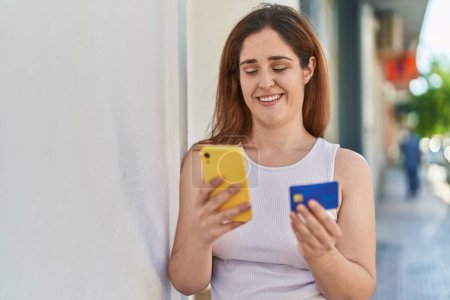 Foto de Mujer joven usando smartphone y tarjeta de crédito en la calle - Imagen libre de derechos