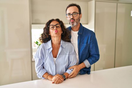 Foto de Middle age couple standing together looking at the camera blowing a kiss on air being lovely and sexy. love expression. - Imagen libre de derechos