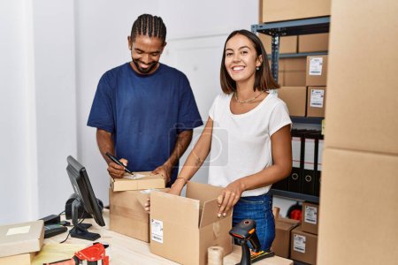 Téléchargez les photos : Homme et femme partenaires commerciaux emballage paquet de travail à l'entrepôt - en image libre de droit
