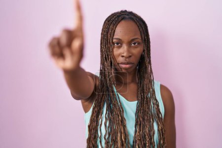 Photo for African american woman standing over pink background pointing with finger up and angry expression, showing no gesture - Royalty Free Image