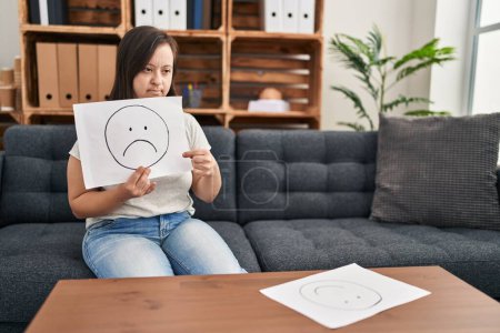 Foto de Síndrome de Down paciente que tiene sesión de psicología que apunta a la emoción triste en la clínica - Imagen libre de derechos