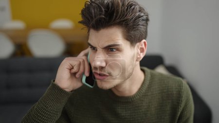 Téléchargez les photos : Young hispanic man talking on the smartphone with unhappy expression at home - en image libre de droit