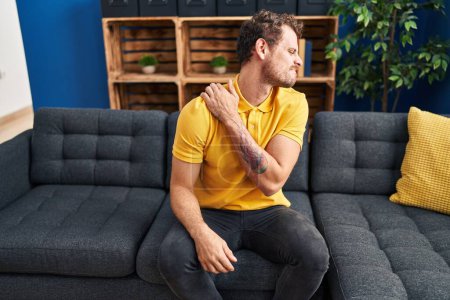 Photo for Young hispanic man suffering for backache sitting on sofa at home - Royalty Free Image