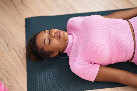 Photo for African american woman relaxed lying on yoga mat at street - Royalty Free Image