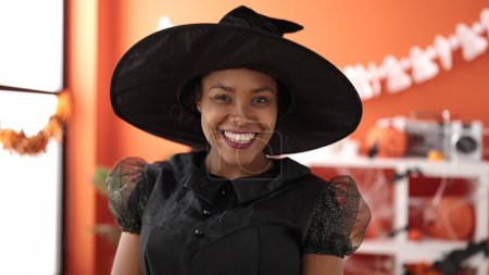 Photo for African american woman wearing witch costume having halloween party at home - Royalty Free Image