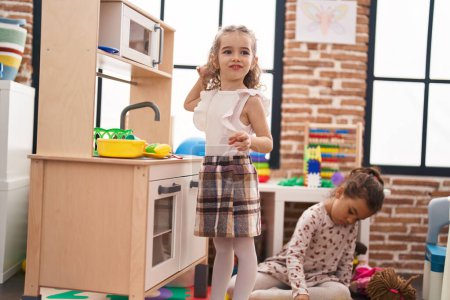 Téléchargez les photos : Deux enfants jouent avec la cuisine de jeu debout à la maternelle - en image libre de droit