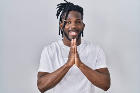 Photo for African man with dreadlocks wearing casual t shirt over white background praying with hands together asking for forgiveness smiling confident. - Royalty Free Image