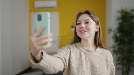Photo for Young blonde woman having video call standing at home - Royalty Free Image