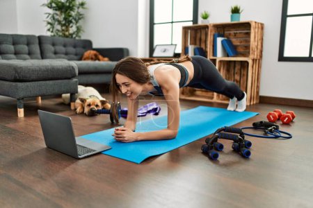Photo for Young hispanic woman smiling confident having online abs exercise class at home - Royalty Free Image