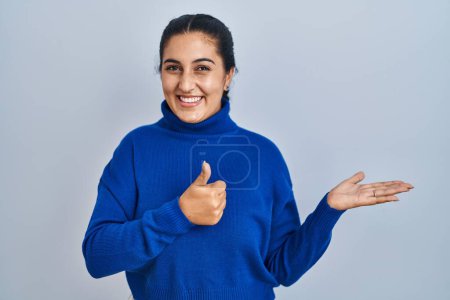 Téléchargez les photos : Jeune femme hispanique debout sur fond isolé montrant la main de la paume et faisant un geste correct avec les pouces levés, souriant heureux et joyeux - en image libre de droit